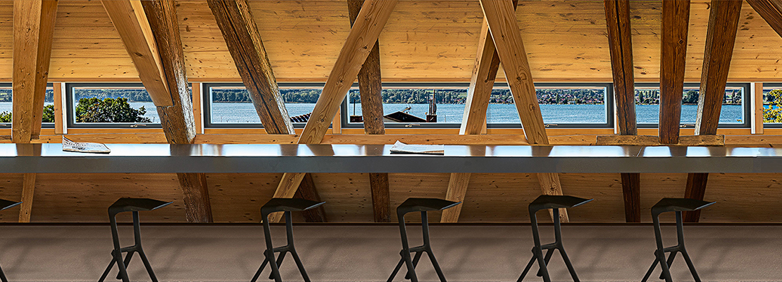 Lesesaal der Stadtbibliothek StaBi: Dachgeschoss mit Seeblick, Holzbalken, Stehtische und Stühle.